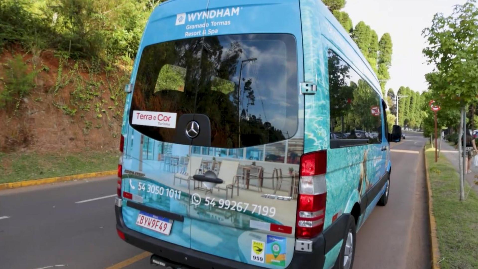 Wyndham Gramado Termas Resort & Spa Екстер'єр фото The image shows the rear side of a van or shuttle bus. The van is wrapped in a promotional design featuring the Wyndham hotel brand, with an advertising message for "Terra & Cor." The vehicle includes contact numbers and a logo. It appears to be on a